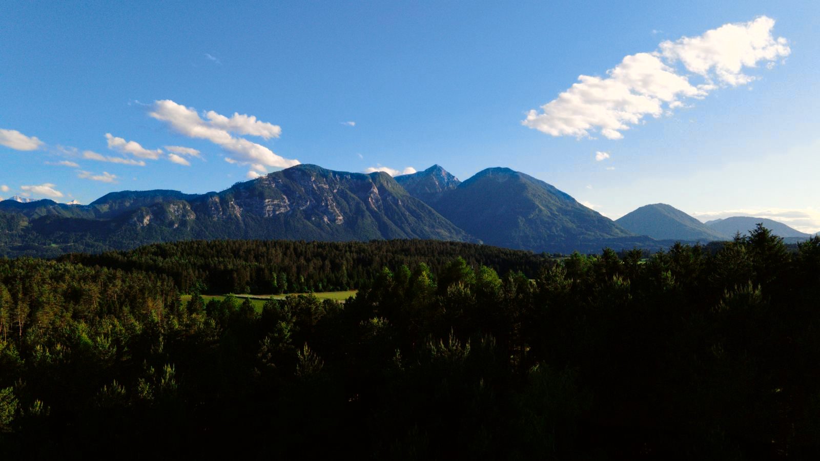 Bergpanorama Südkärnten über bewaldeten Hügeln unter blauem Himmel