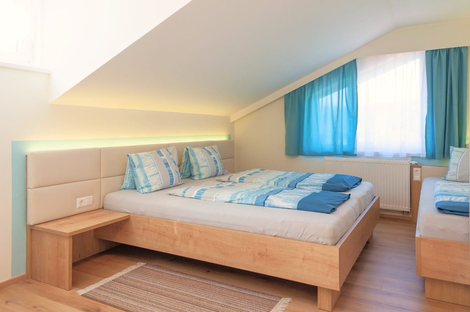 Vierbettzimmer mit Doppelbett, Einzelbett und türkisen Vorhängen