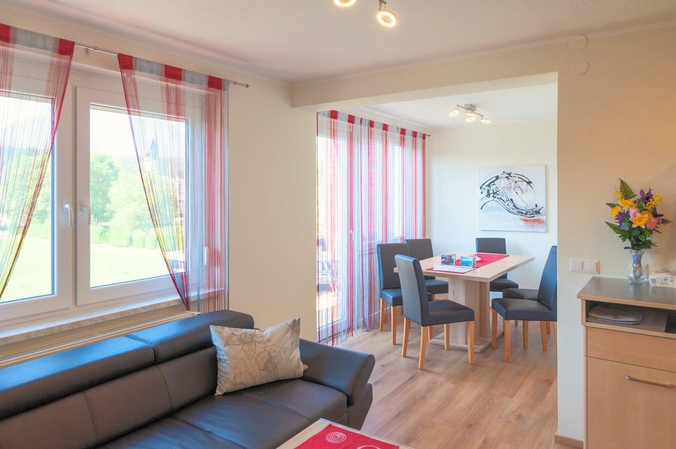 Wohnzimmer mit Ledersofa, Essplatz und Balkontür