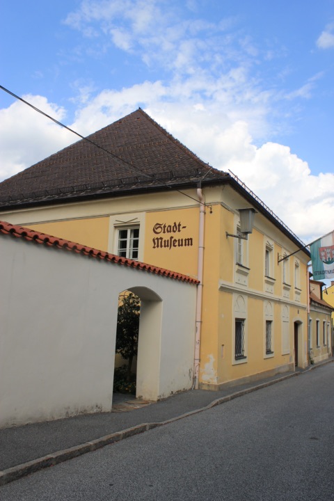 Das gelbe Gebäude des Stadtmuseums in der Faschinggasse von Völkermarkt mit der Aufschrift „Stadt-Museum“ unter blauem Himmel