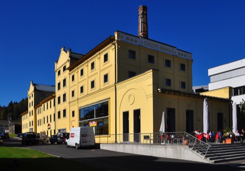 Gelbes Gebäude der Schleppe-Brauerei mit Schornstein und Terrasse in Klagenfurt