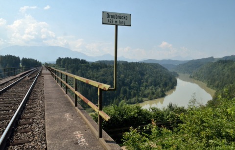 Blick von der Jauntalbrücke auf die Drau, die sich durch ein bewaldetes Tal schlängelt