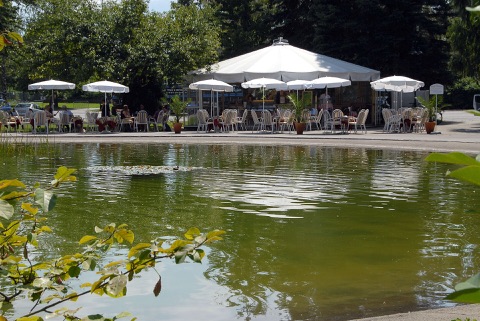 Café mit weißen Sonnenschirmen am Teich im Europapark Klagenfurt
