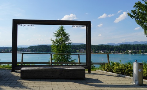 Großer Holzrahmen mit Bank auf einer Terrasse, durch den man über den Klopeiner See blickt