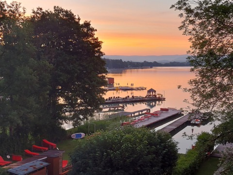 Sonnenaufgang über dem Klopeiner See, im Vordergrund Badestege mit roten Liegen und einem Pavillon