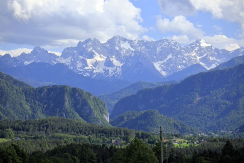 Blick vom Grabelsdorfer Kreuz über bewaldetes Hügelland auf die schneebedeckten Steiner Alpen