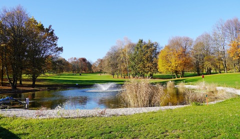 Teich mit Fontäne und herbstliche Bäume auf dem Golfplatz in St. Kanzian