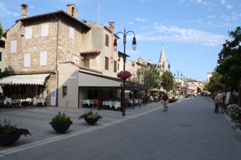 Fußgängerzone in der Altstadt von Grado mit Lokalen und dem Glockenturm von Sant'Eufemia