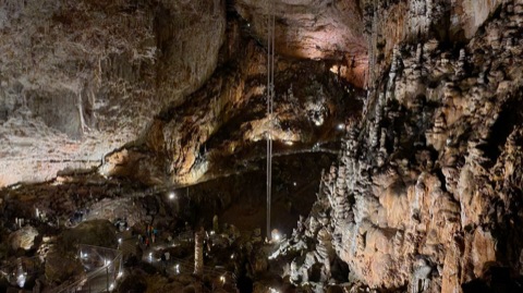 Blick über die beleuchtete Haupthalle der Grotta Gigante mit Tropfsteinen und Besucherweg