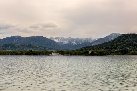 Blick über den Wörthersee auf die Halbinsel Maria Loretto mit dem Schloss, dahinter die Košuta