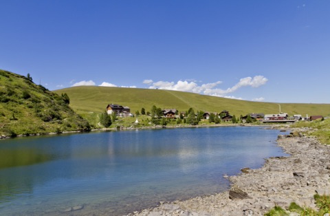 Der Falkertsee in den Nockbergen mit umliegenden Almhängen