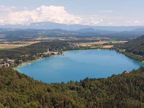 Der Klopeiner See von der Aussichtsplattform am Kitzelberg, umrahmt von Wald und Feldern