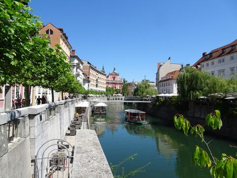 Die Ljubljanica in der Altstadt von Ljubljana mit Uferpromenade, Ausflugsboot und Bäumen