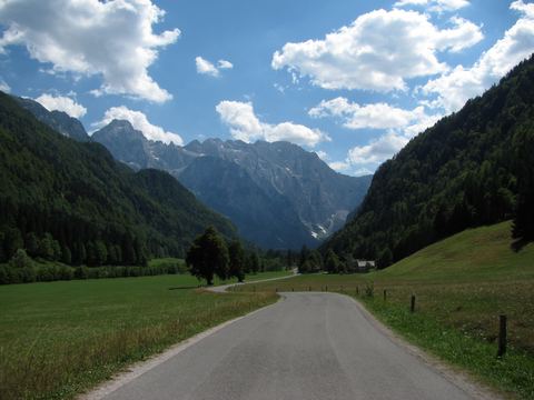 Straße durch das grüne Logartal, umrahmt von den Gipfeln der Steiner Alpen