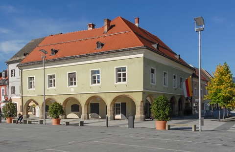 Altes Rathaus mit Arkadengang und rotem Ziegeldach am Hauptplatz der Völkermarkter Altstadt, davor Blumentöpfe und Laternen