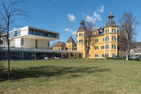 Gelbes Schloss Velden mit Türmen und moderner Seespitz-Anbau am Schlosspark