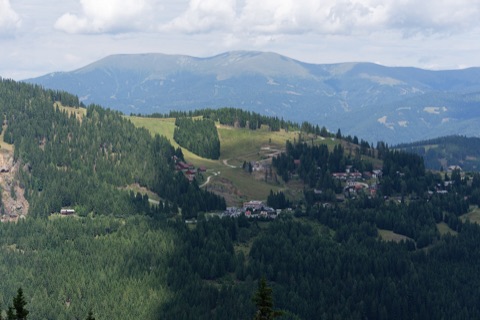 Sommerlicher Blick auf die Hütten und Pisten am Klippitztörl, dahinter die Saualpe