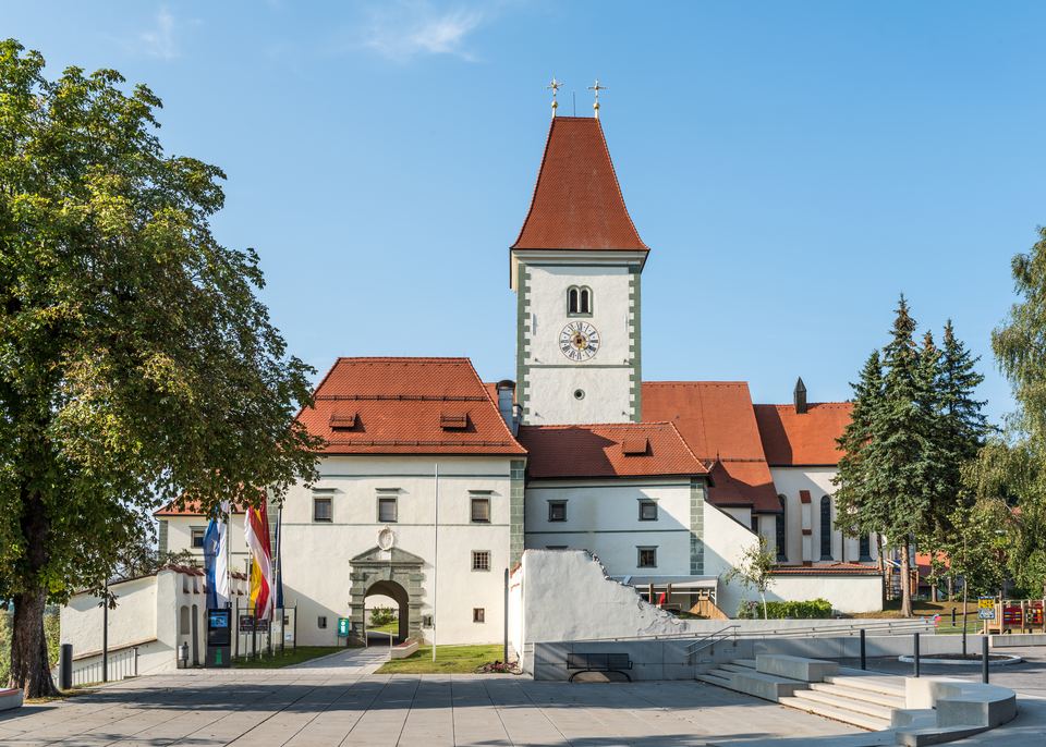 Stift Eberndorf mit Uhrturm und roten Dächern unter blauem Himmel