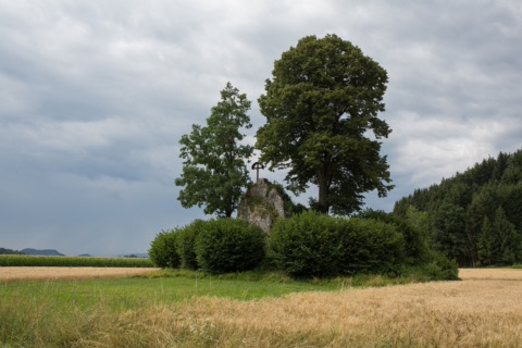 Felsblock mit Kreuz, Linde und Eiche mitten in einem Getreidefeld im Jauntal