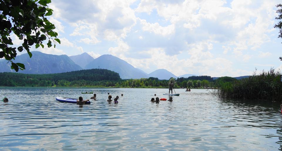 Badende und Stand-up-Paddler am Turnersee vor den Karawanken