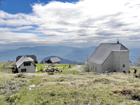 Gipfelbereich der Uršlja gora mit Berghütte und der weißen Kirche St. Ursula, dahinter Hügelland