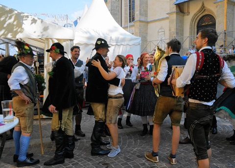 Musikanten und Tanzpaare in Tracht beim Villacher Kirchtag vor der Stadtpfarrkirche
