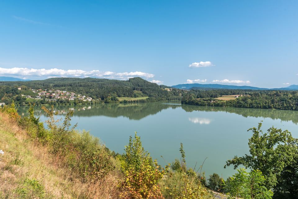 Der Völkermarkter Stausee der Drau an einem sonnigen Sommertag mit grünen Ufern