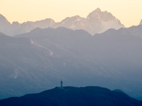 Bewaldeter Pyramidenkogel mit Aussichtsturm vor den Karawanken im Abendlicht