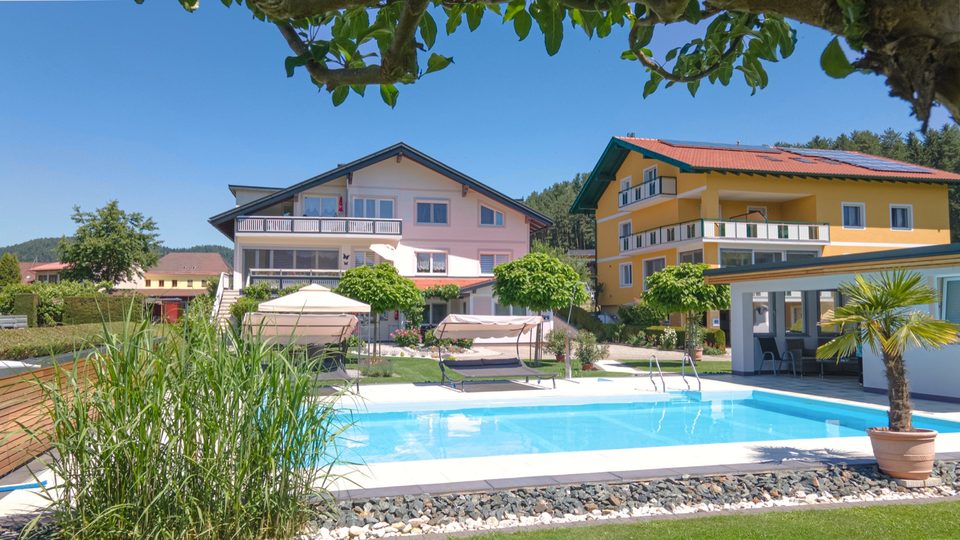 Garten mit Ziergräsern, Pool und Haus unter strahlend blauem Himmel