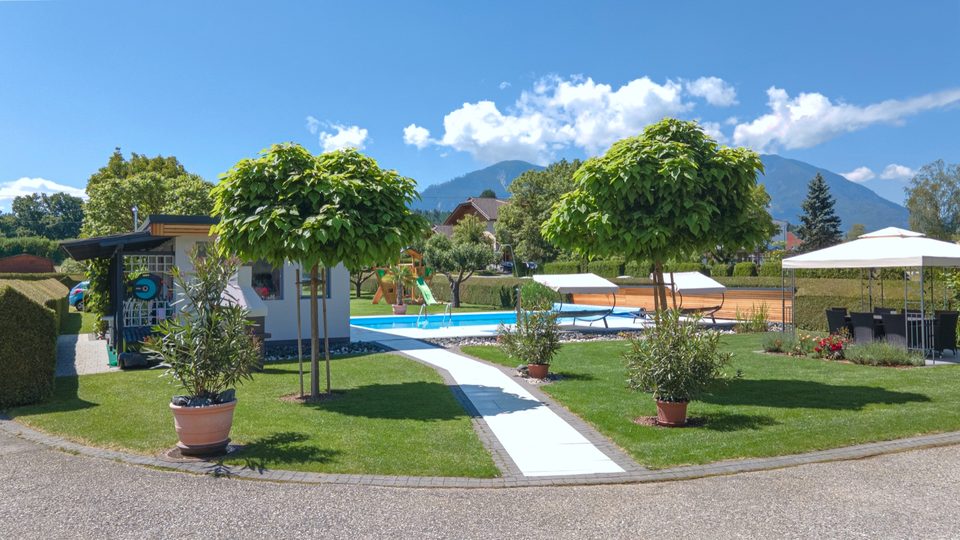 Gartenweg mit Kugelbäumen, Pool und Bergkulisse