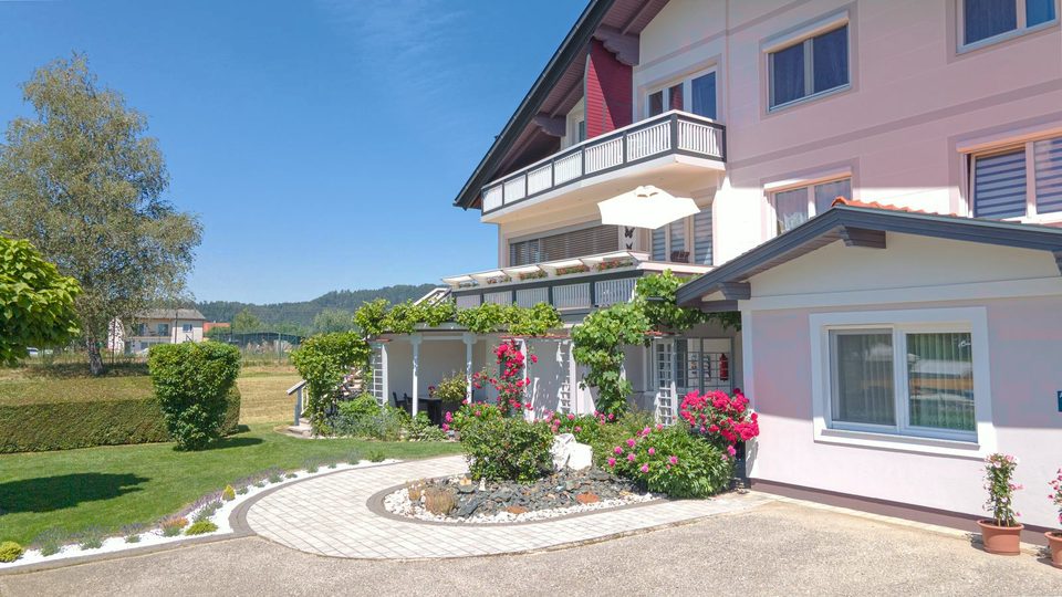 Gepflasterte Einfahrt mit Rosenbeet und Pergola vor dem Ferienhaus