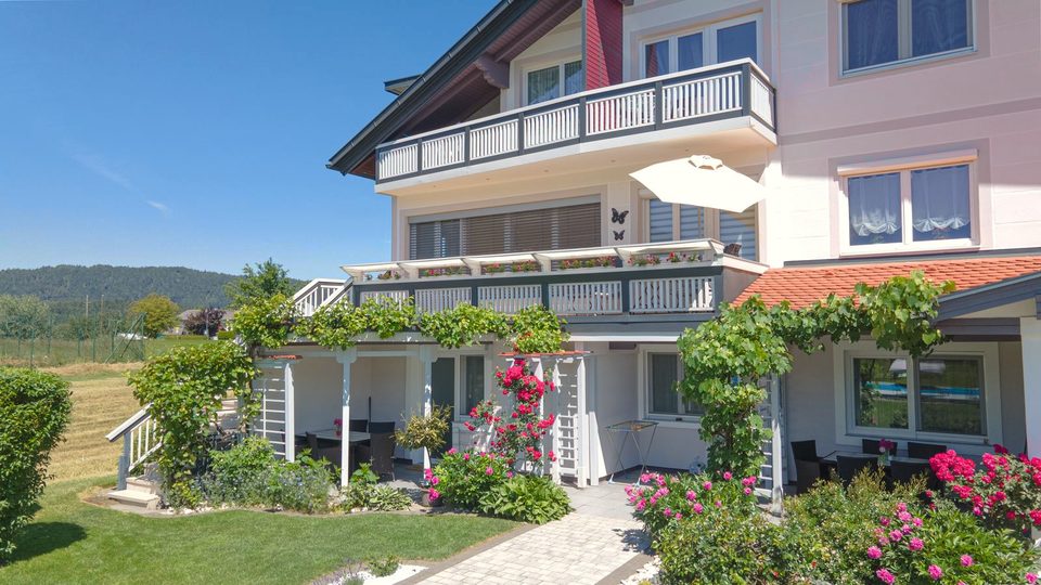Haus mit Balkonen, Sonnenschirm und blühenden Rosen an der Terrasse