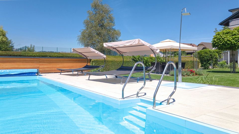 Edelstahl-Poolleiter und Sonnenliegen am Beckenrand