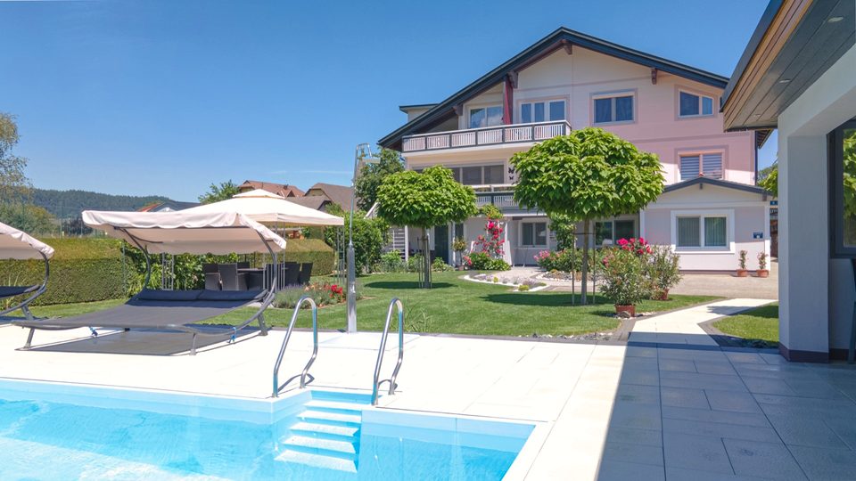 Pooltreppe, Doppelliegen und Bäumchen vor dem Haus an einem Sommertag