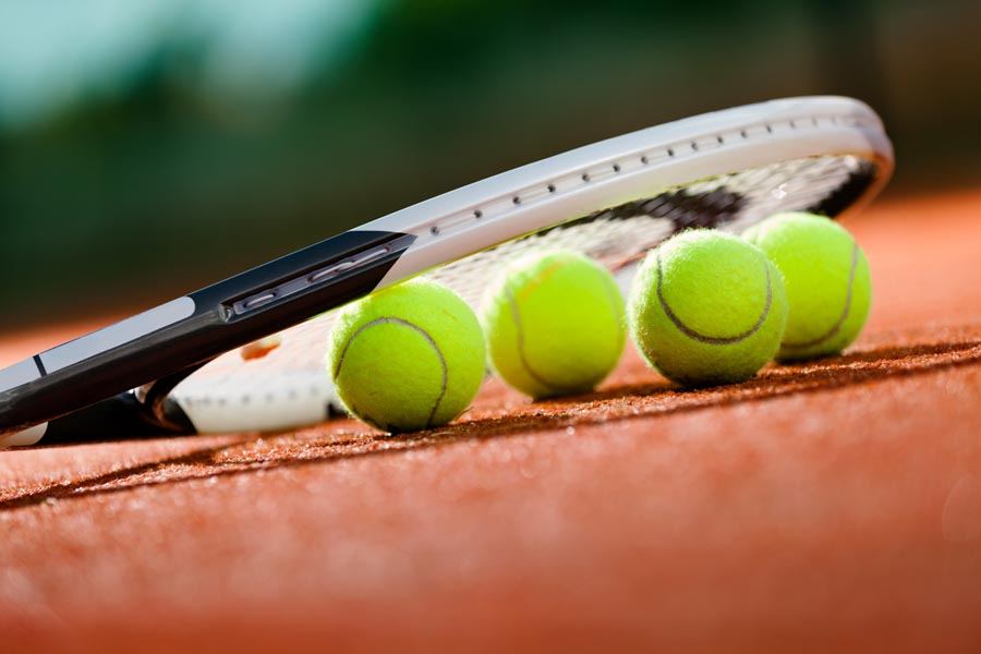 Tennisschläger und Bälle auf einem Sandplatz