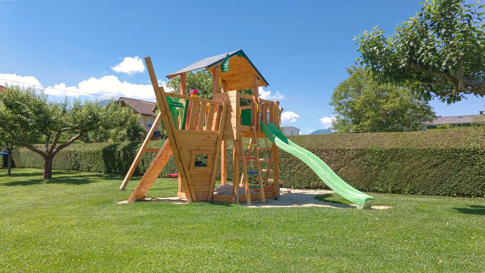 Spielturm mit grüner Rutsche auf der großen Spielwiese
