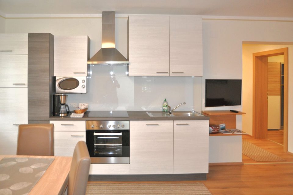Küchenzeile mit Backofen, Mikrowelle, Kaffeefiltermaschine und Dunstabzug