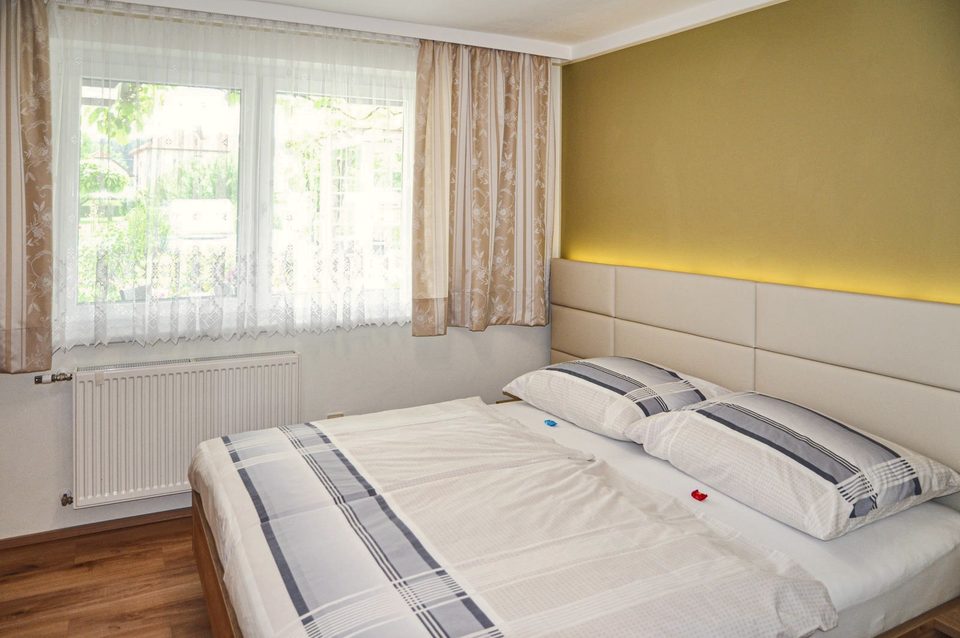 Doppelzimmer mit olivgrüner Akzentwand und großem Fenster
