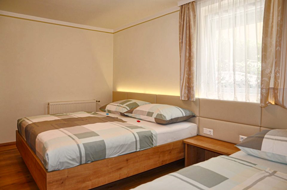 Dreibettzimmer mit Doppelbett und Einzelbett unter dem Fenster
