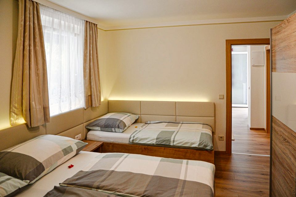 Dreibettzimmer mit Kleiderschrank und Tür zum eigenen Bad
