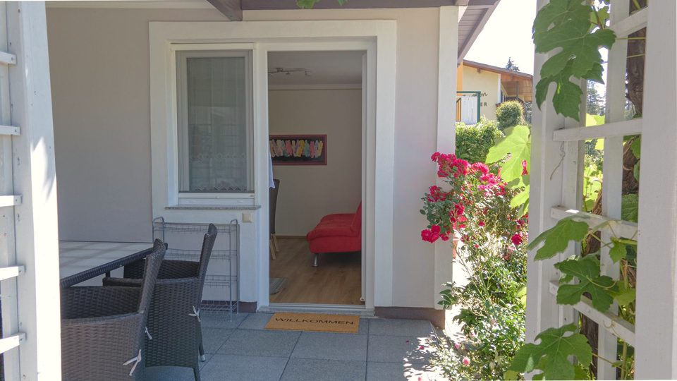 Terrasse unter der Rosenpergola, durch die Tür der Wohnraum