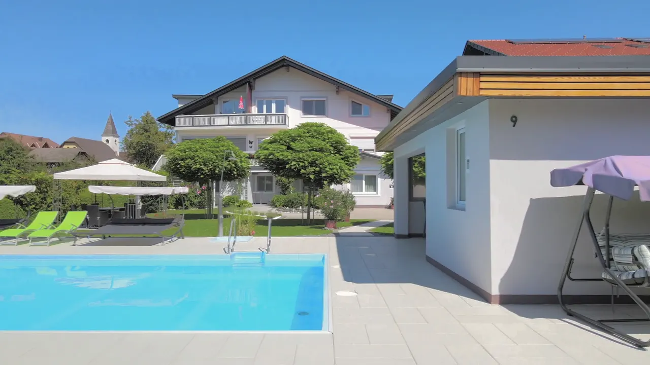 Kamerafahrt am Pool entlang zur Badehütte mit Hollywoodschaukel und Palme