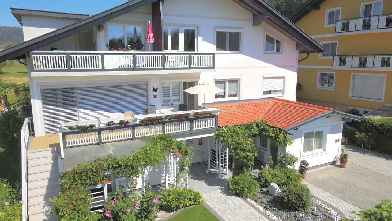 Die Vorderseite des Hauses mit Balkonen, Terrasse und Garten
