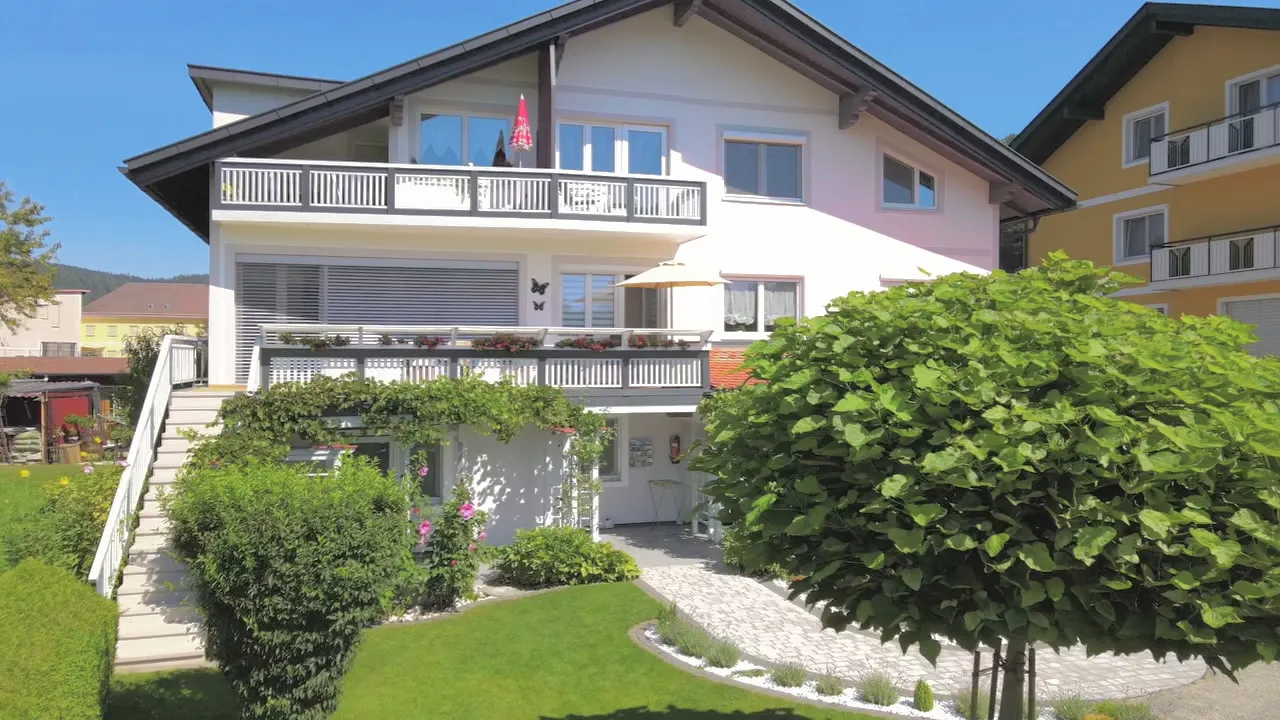 Kamerafahrt an einem Kugelbaum vorbei auf das Haus mit seinen Balkonen zu