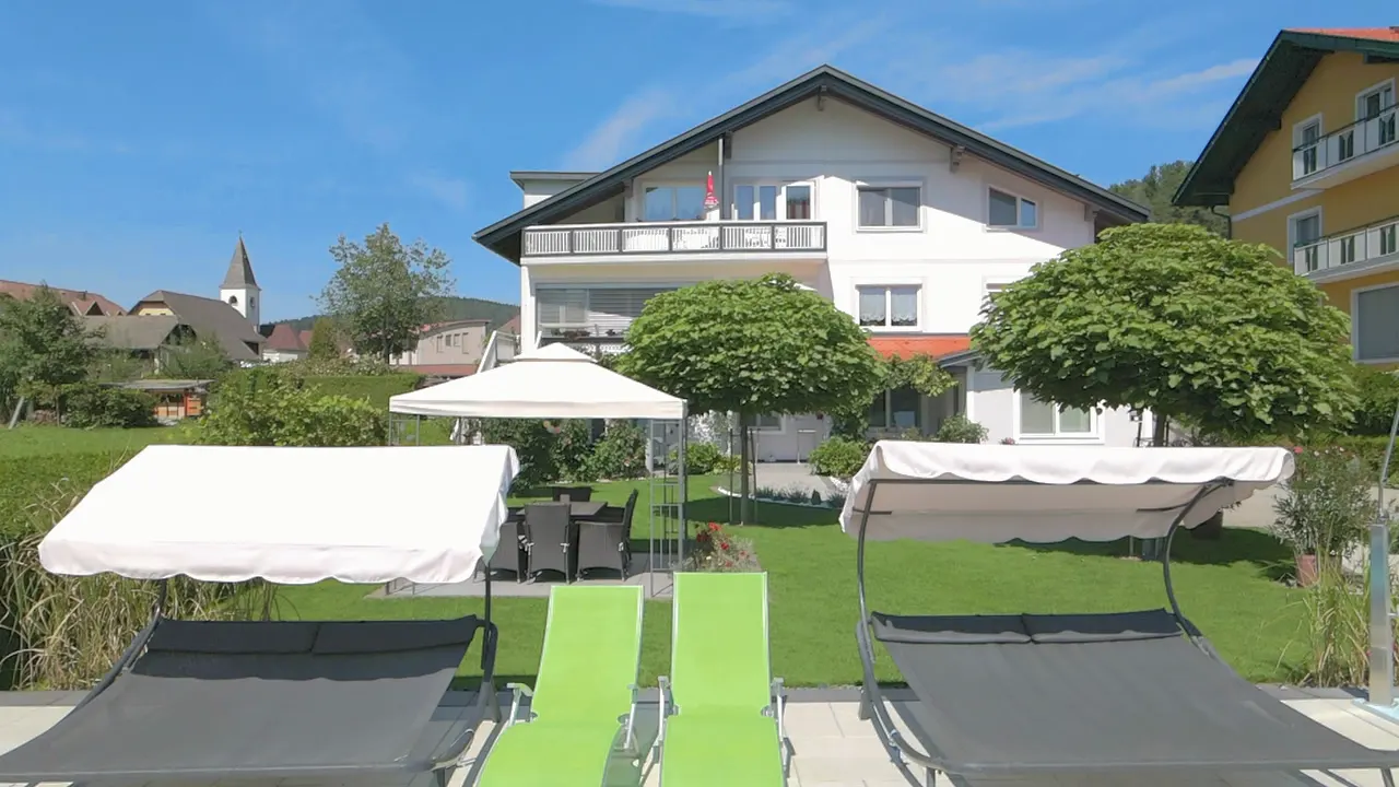 Fahrt über die Liegewiese an Doppelliegen und Sonnenliegen vorbei zum Pavillon, dahinter das Haus