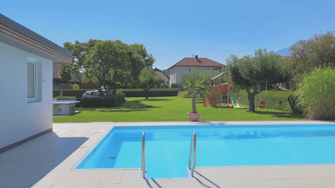 Blick über den Pool mit Leiter in den Garten mit Spielturm